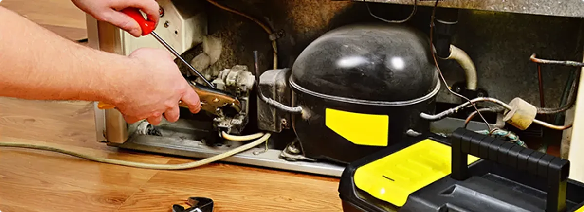 Refrigerator repair technician fixing the compressor and wiring in Chelsea, MA