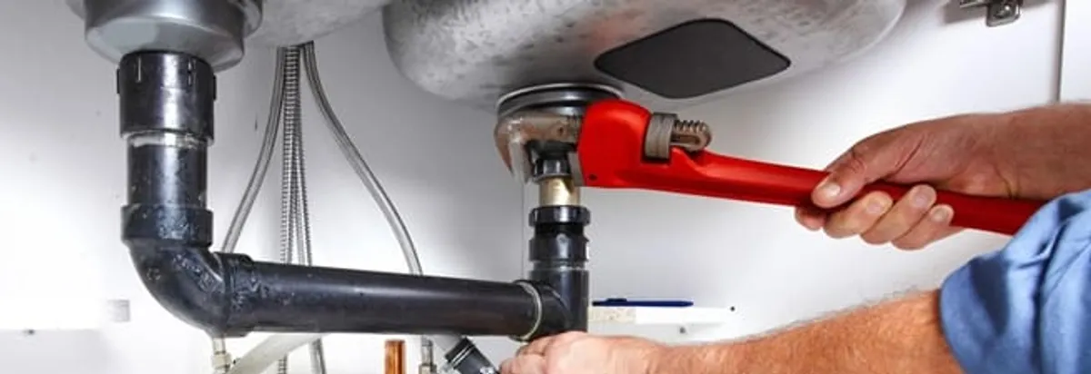 Garbage disposal repair technician tightening the sink drain and disposal connection in Boston, MA