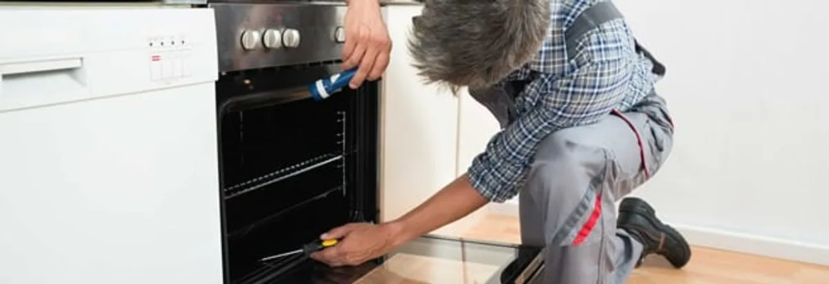 Oven repair technician inspecting and servicing an electric oven in Boston, MA