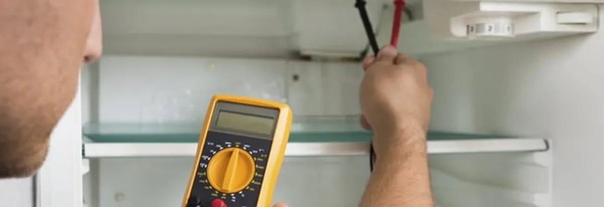 Refrigerator repair technician testing electrical components with a multimeter in Boston, MA